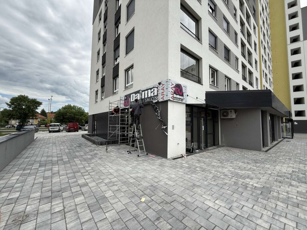 Radnici montiraju osvijetljenu reklamu salona „Dalma“ na novoj lokaciji uoči otvaranja
