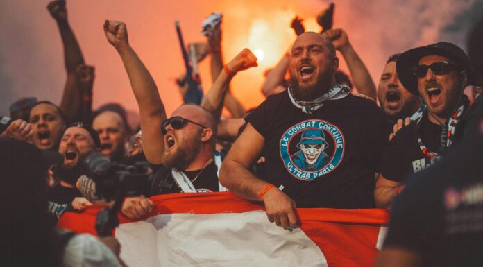 Najveći derbiji Balkana – sportski spektakli koji dijele publiku Njaveći derbiji Bakana. Fudbal. Navijači. Fudbalski navijači pjevaju dok idu na utakmicu držeći zastavu i upaljene baklje.