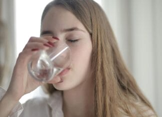 Devojka pije vodu iz čaše