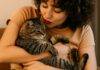 Hug your cat day, mačke, mačke i ljudi, Žena sa crvenim ružem nježno grli svoju tigrastu mačku u toplom ambijentu