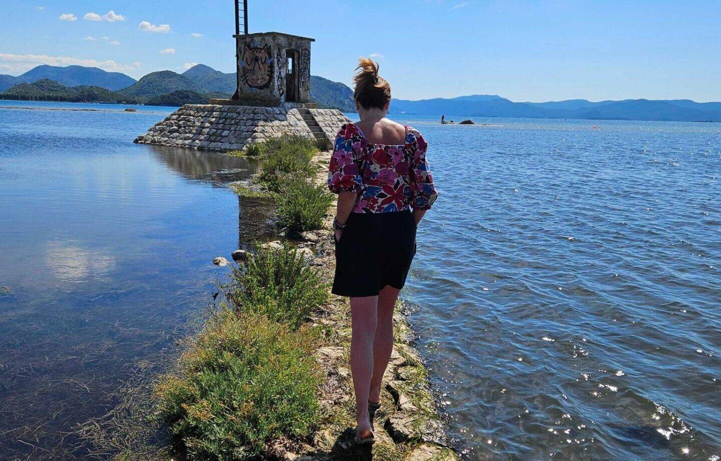 početak ljeta 2025, ljeto, Žena hoda bosim stopalima po kamenitom putu kroz vodu