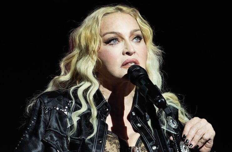 Madonna na pozornici u crnoj kožnoj jakni i s akustičnom gitarom
