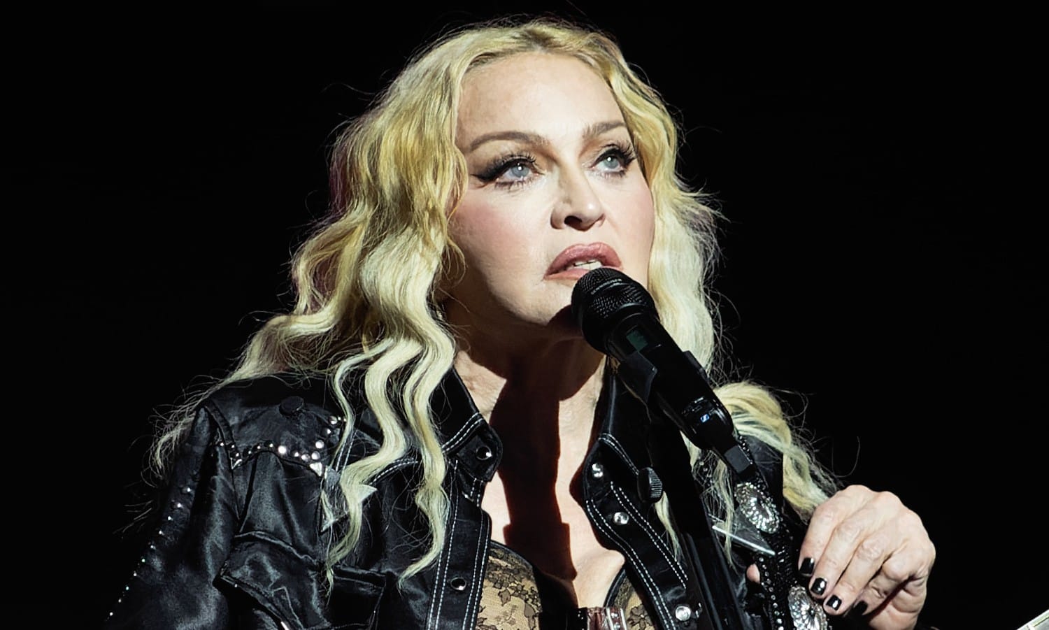 Madonna naslovna Madonna na pozornici u crnoj kožnoj jakni i s akustičnom gitarom