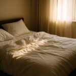 Depresija nakon odmora – zgužvan krevet obasjan jutarnjim svjetlom koje ulazi kroz zavjese