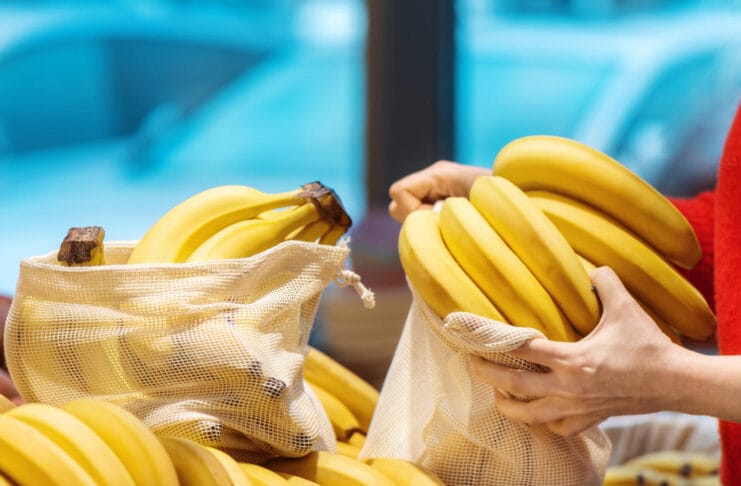 Woman picking bananas in a reusable bag. Ecology, Earth Day thematics