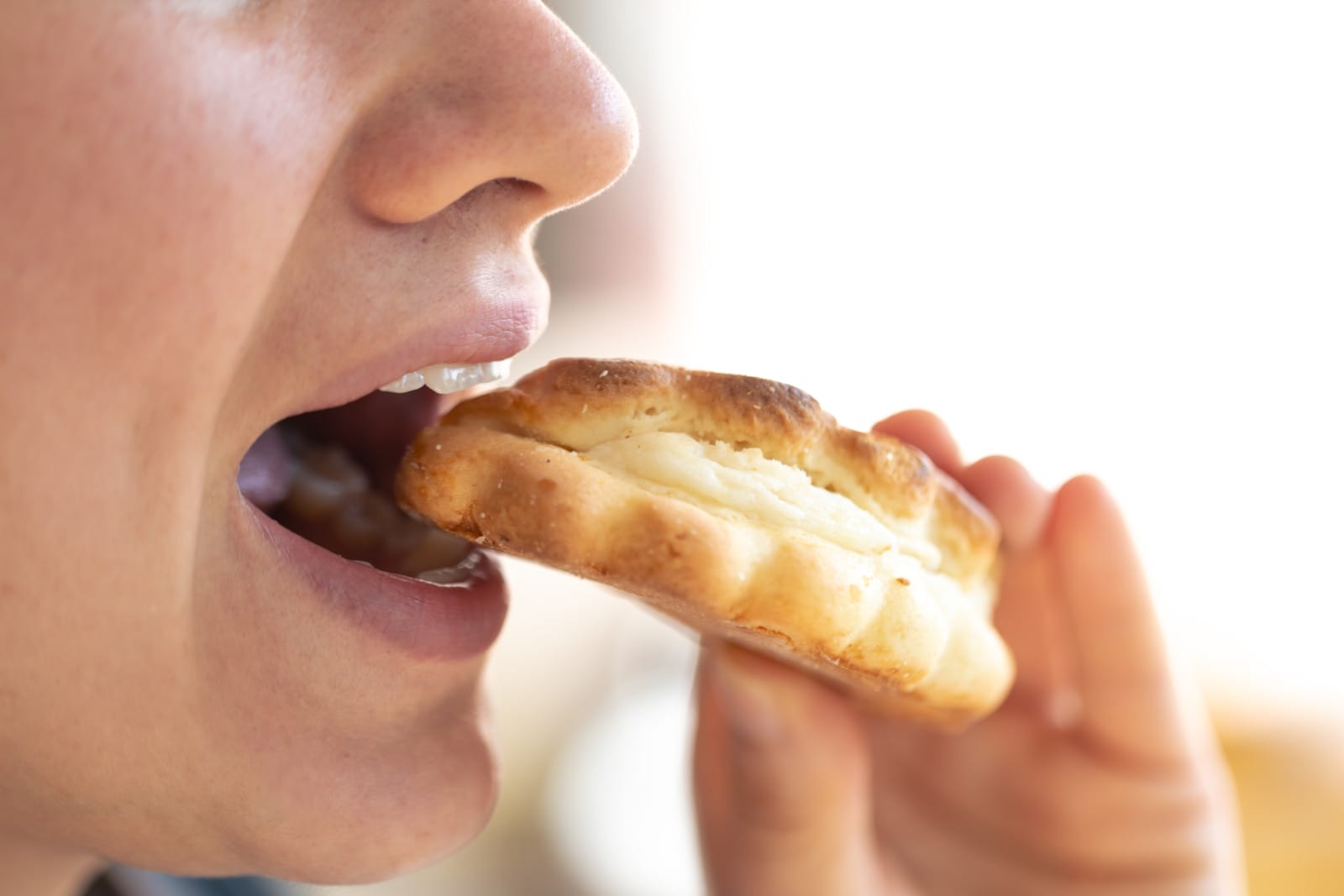 Detailed shot of a woman eating fresh bun.