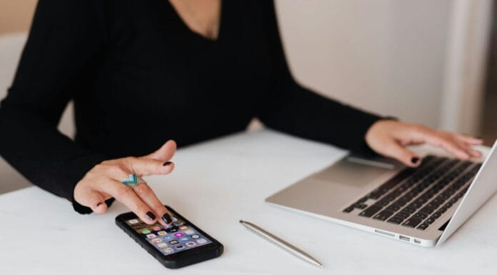 Žena koristi mobilni telefon dok radi na laptopu