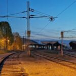 Ljubav u Sarajevu, Željeznička stanica u Sarajevu u sutonu, sa prugama koje se račvaju i toplim svjetlima koja nagovještavaju dolazak i odlazak vozova.