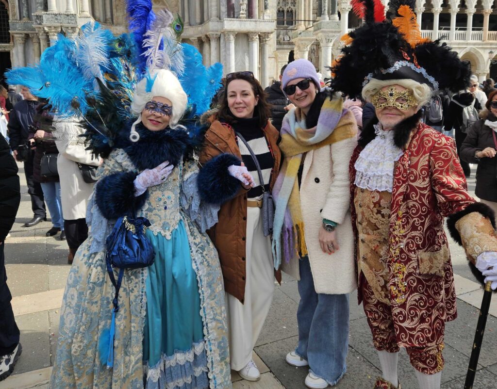 Venecijanski karneval, Karnevalski kostimi s perjem i maskama na Trgu svetog Marka u Veneciji, grupa pozira za fotografiju