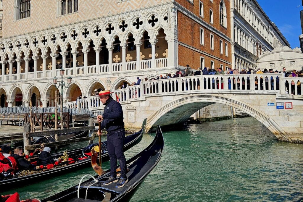 Venecijanski karneval, Gondole na kanalu u Veneciji, gondolijer stoji i upravlja, u pozadini arhitektura Trga svetog Marka
