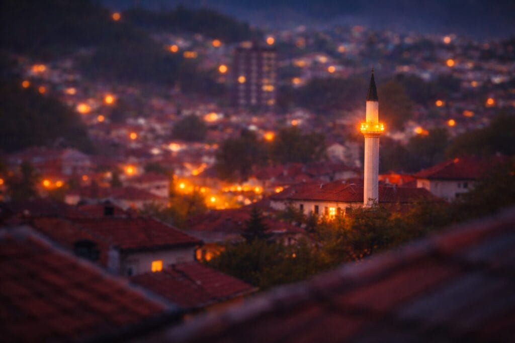 Najvažnije noći u ramazanu – Lejletul-Bedr, Lejletul-Kadr i posebni trenuci mjeseca posta; Akšam u bosanskom gradu, osvijetljena munara sa kandiljima iznad krovova tokom ramazana