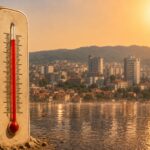 Toplotni val u Tuzli, termometar u prvom planu i gradska panorama u izmaglici od vrućine