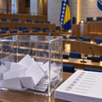 Kompenzacijske liste: Ko ima dodatnu priliku za mandat? Glasačka kutija i kandidatska lista ispred parlamentarnih klupa; Kompenzacijski mandati i izbor zastupnika u parlament.